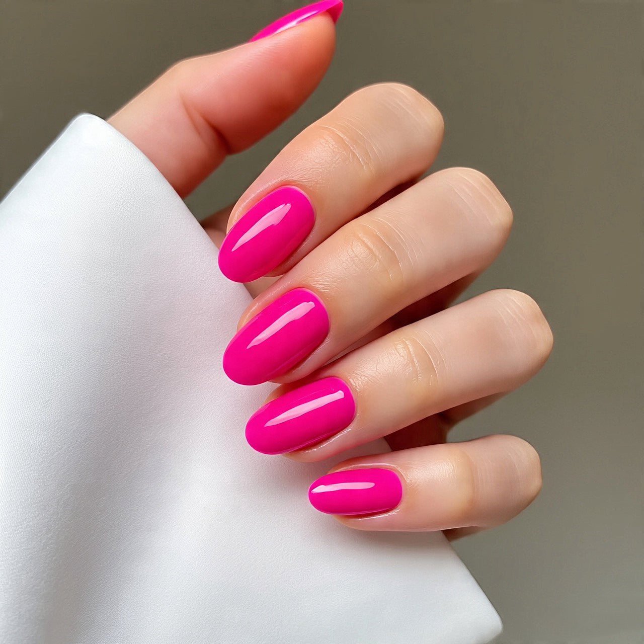 Hand with bright pink nails holding a white object against a neutral background