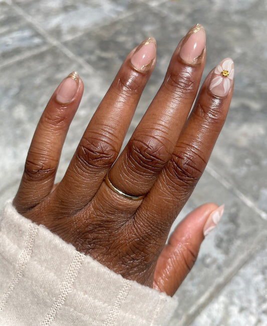 Golden Bloom short almond press-on nails on dark skin – nude base with 3D white flower, gold charm and gold foil tips – Leewa Beauty