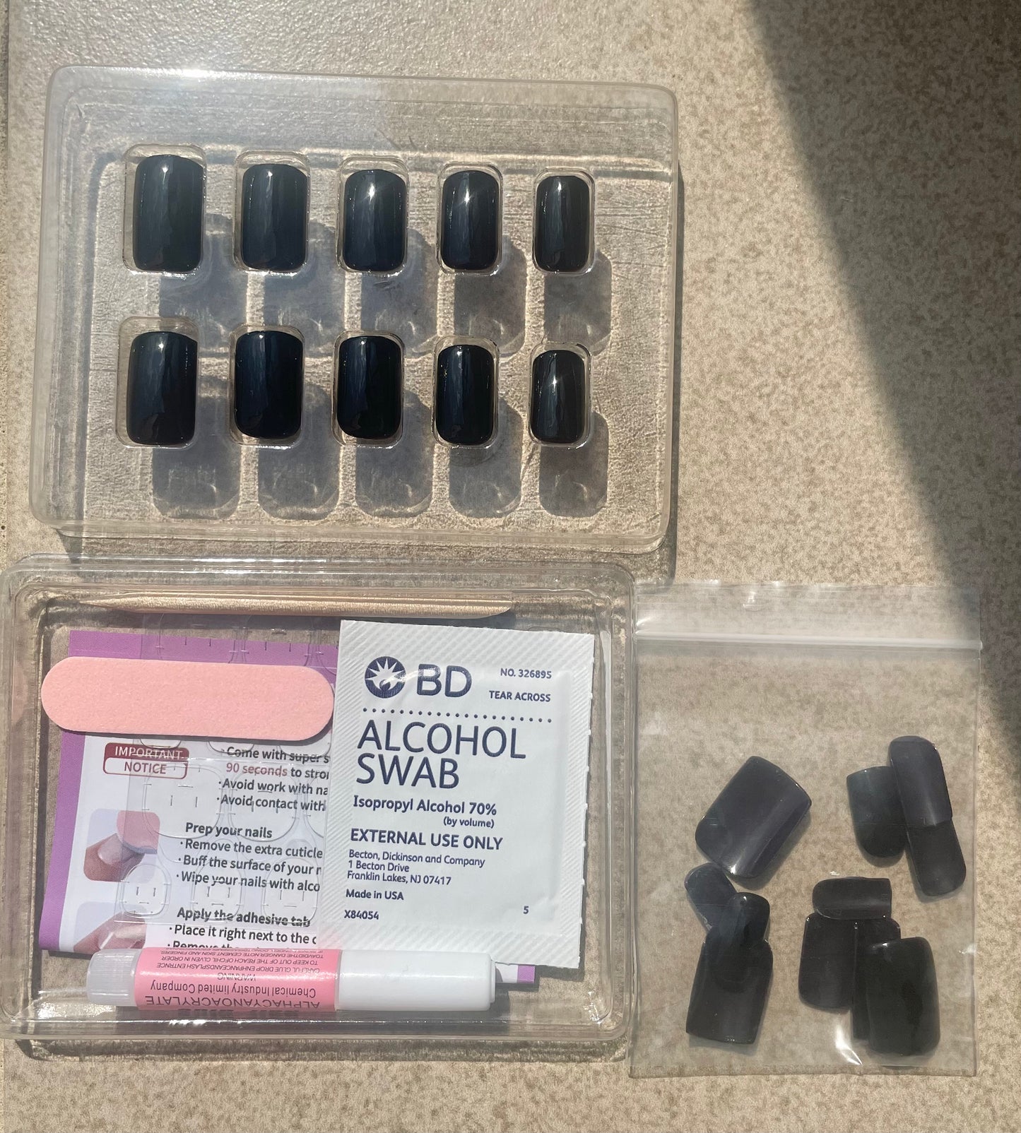 Reusable Noir Square jet black Press-on Nails and Nail Kit which includes nail glue, gel nail tabs, double sided nail file, alcohol pad, user manual, and cuticle stick made by Leewa Beauty