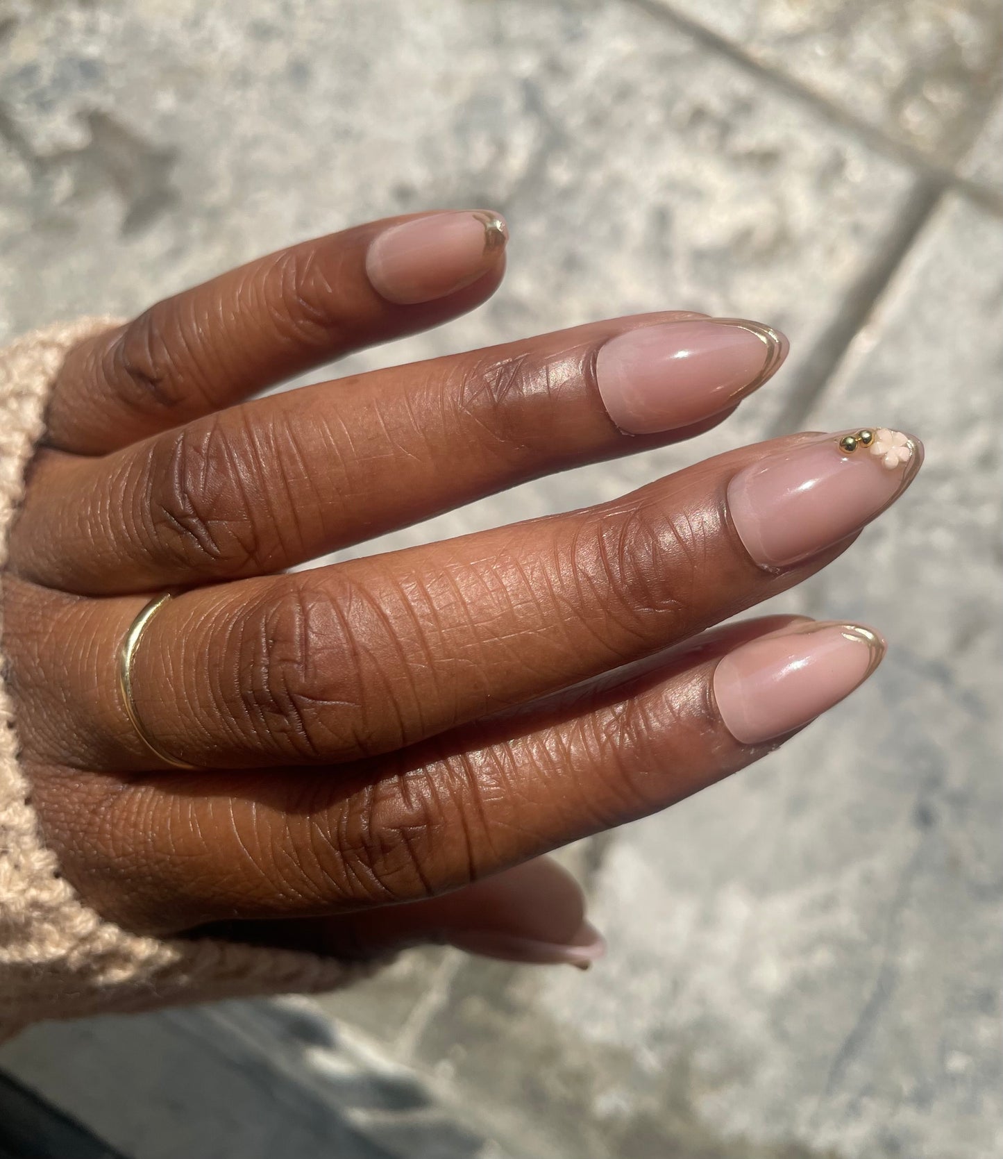 Camellia soft gel almond press-on nails with nude pink finish,  gold French tips, and floral accent by Leewa Beauty