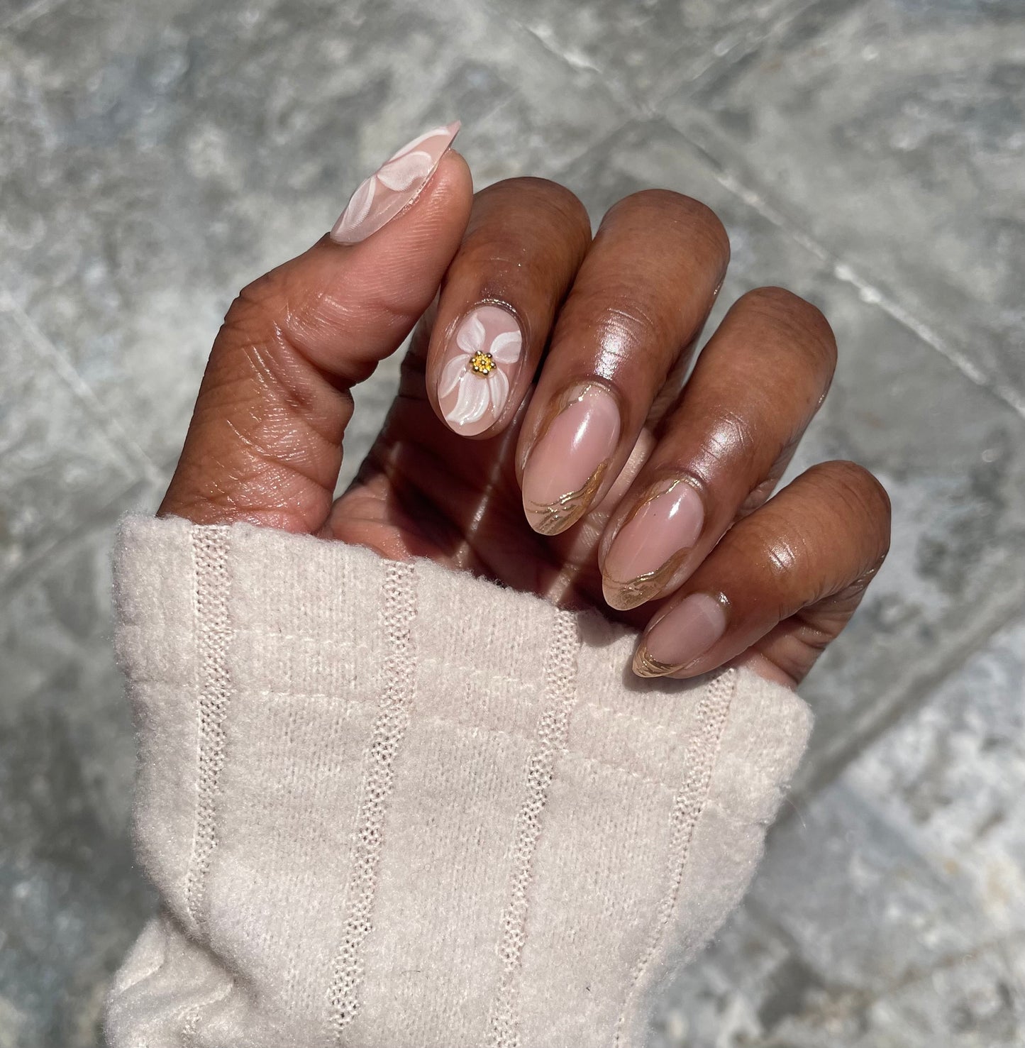 Golden Bloom press-on nails on dark skin tone – short almond with 3D white floral, gold center charm and gold tip accent – Leewa Beauty
