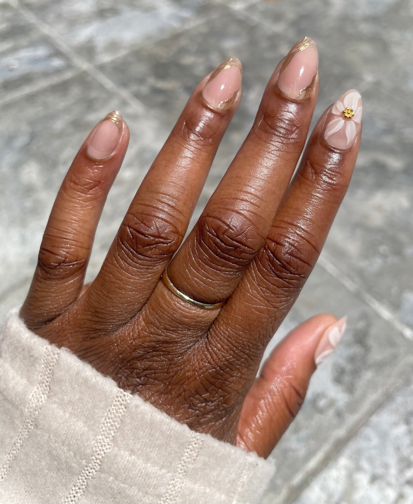 Golden Bloom short almond press-on nails on dark skin – nude base with 3D white flower, gold charm and gold foil tips – Leewa Beauty

