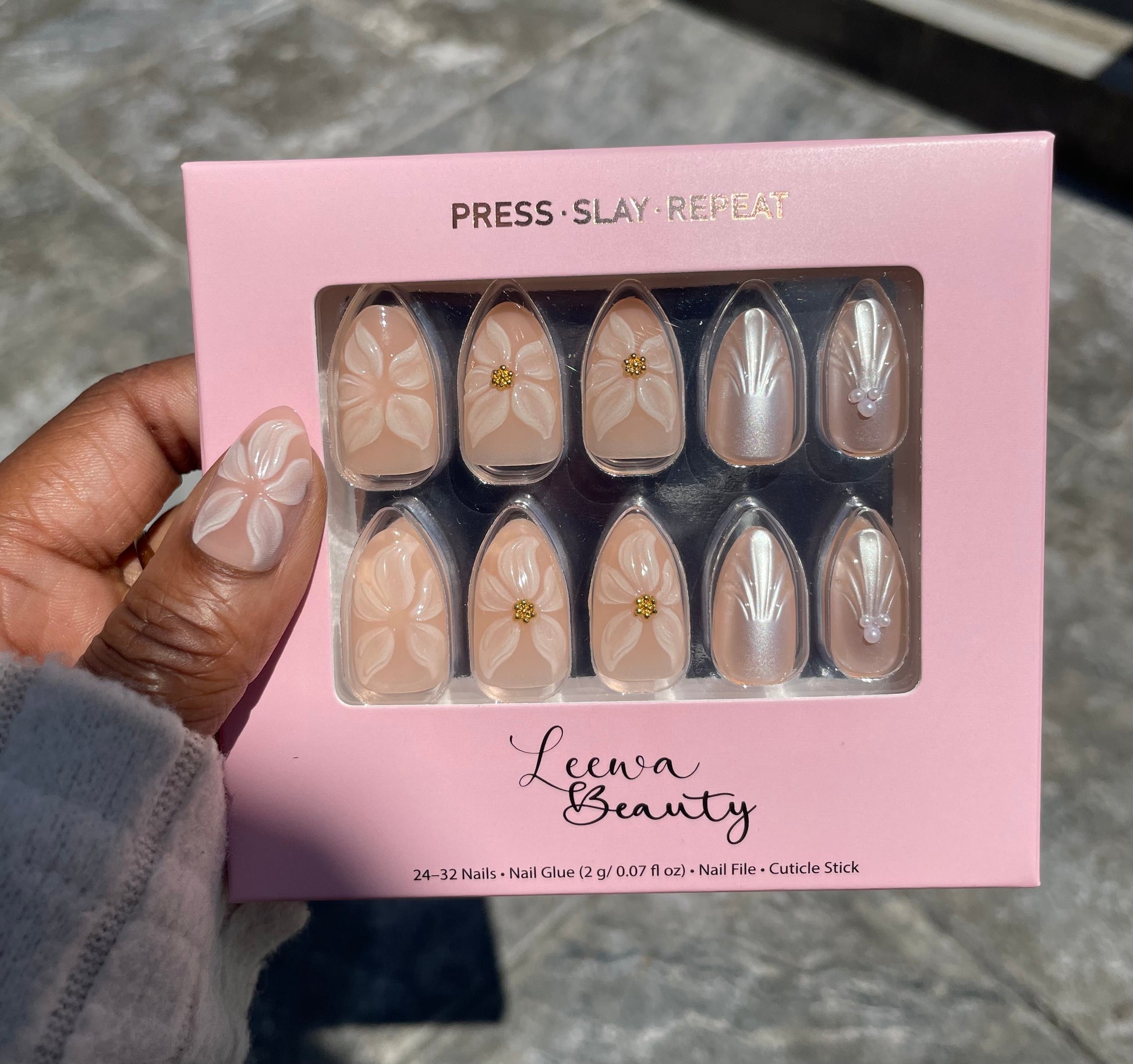 Close-up of Golden Bloom press-on nail with 3D white floral and gold center charm on short almond shape in Leewa Beauty brand box– Leewa Beauty


