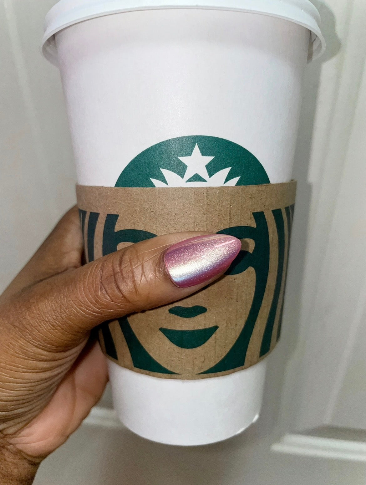 Woman wearing Pink Static chrome soft gel press-on nails while holding a Starbucks coffee. 