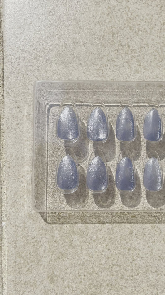 Blue Sea Almond made by Leewa Beauty Reusable almond-shaped press-on nails feature a stunning shade of blue and a breathtaking silver cat eye effect. 