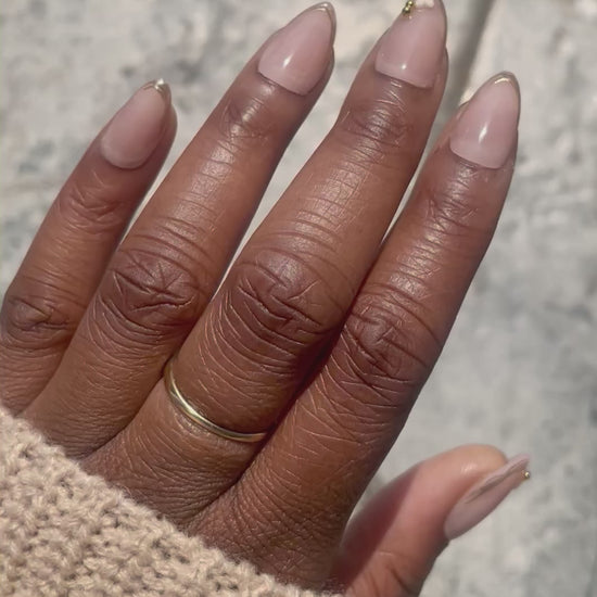 Video showcasing Camellia soft gel almond press-on nails with nude pink finish, gold French tips, and delicate flower accent by Leewa Beauty. 
