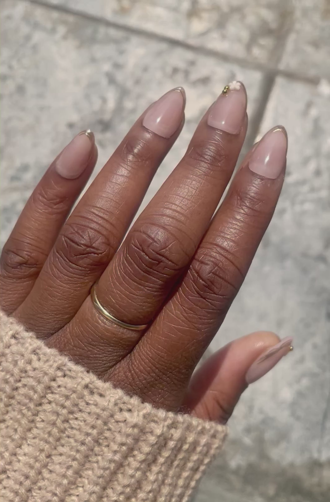 Video showcasing Camellia soft gel almond press-on nails with nude pink finish, gold French tips, and delicate flower accent by Leewa Beauty. 